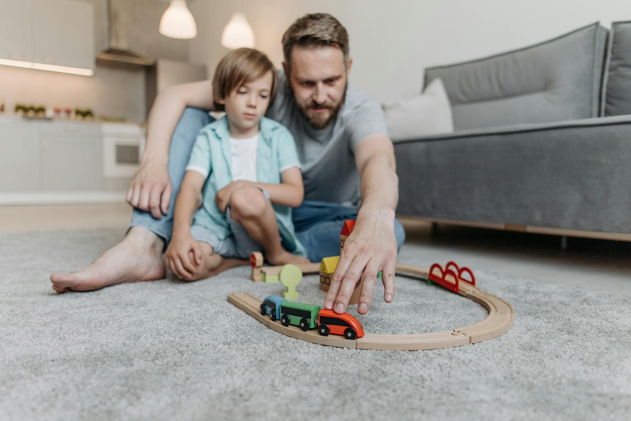 A father and son bonding over a toy train set in their living room, enjoying quality time together.