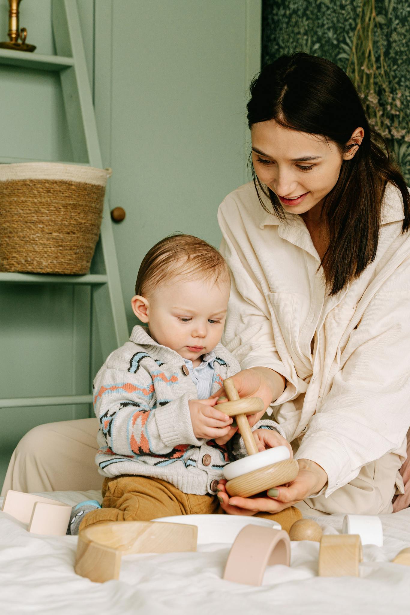 A mother and baby play together with wooden toys in a cozy room, enjoying quality time.