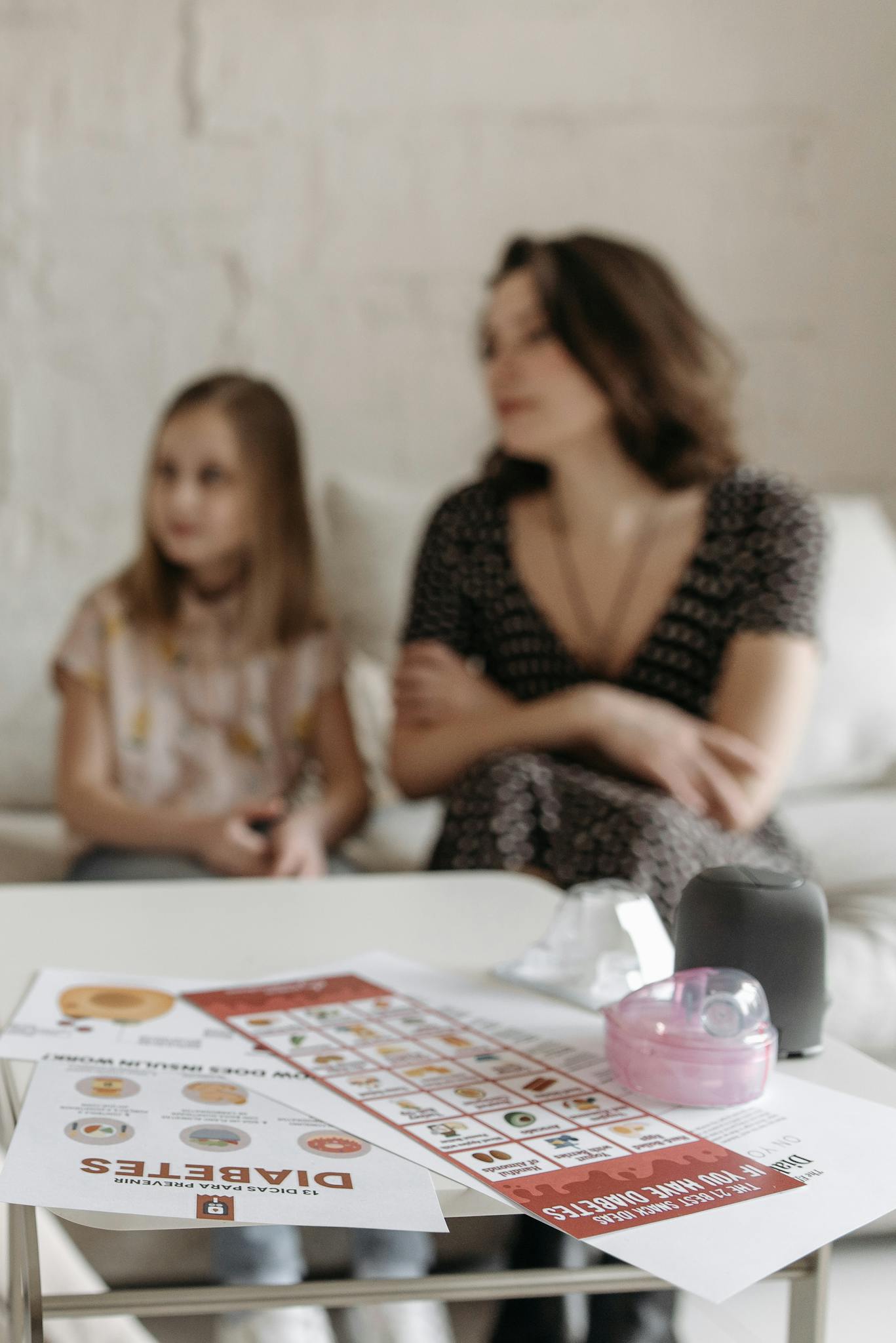 A mother and daughter seated with diabetes pamphlets on the table, engaged in health awareness.