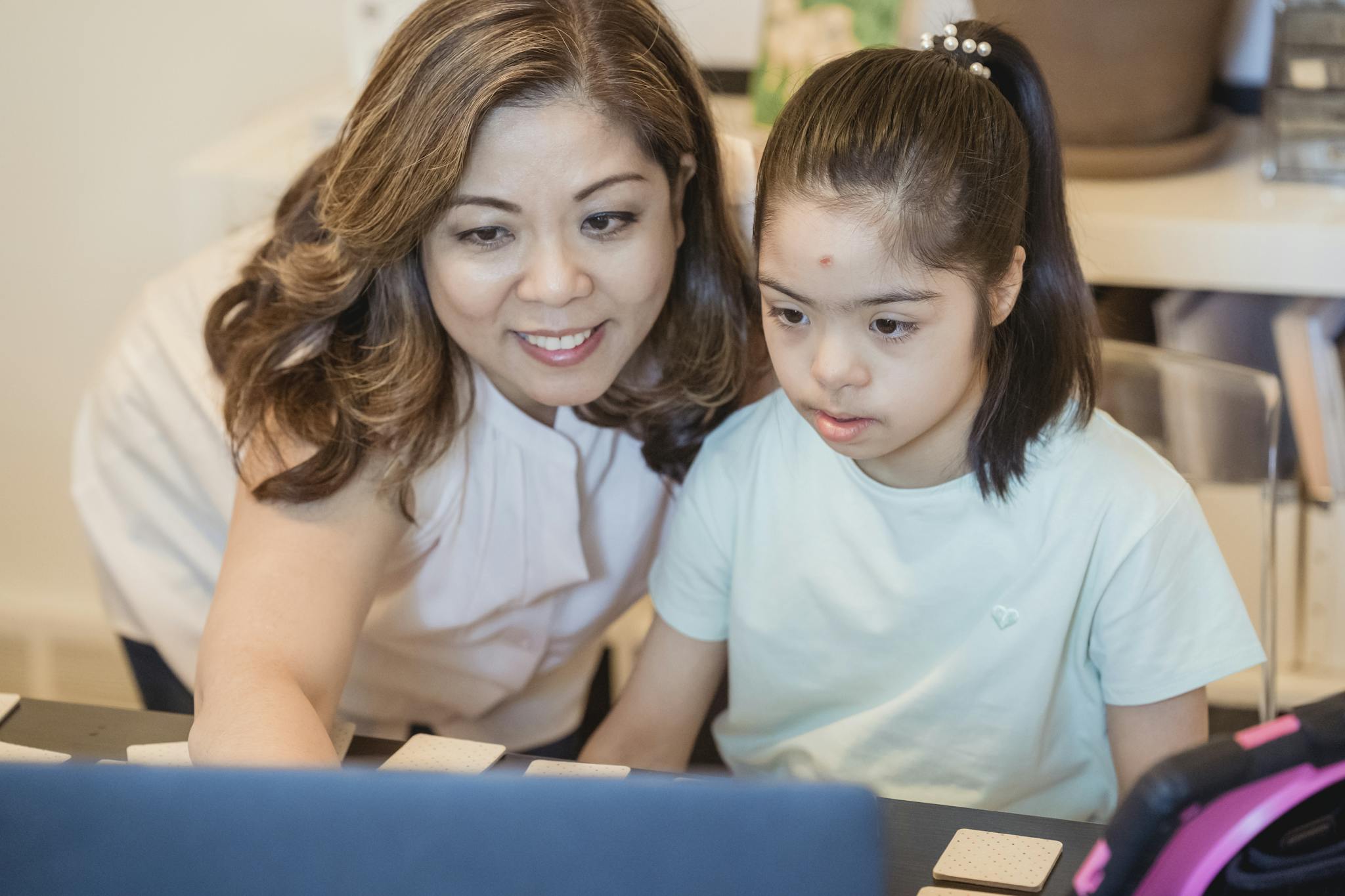 A woman and young girl using a computer together, showcasing family bonding and technology learning.